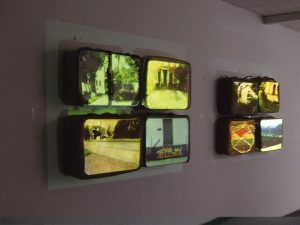 Installation mit Koffern die an der Wand hängen. Darauf werden Bilder projeziert.
