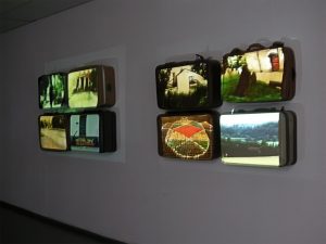 Installation mit Koffern die an der Wand hängen. Darauf werden Bilder projeziert.